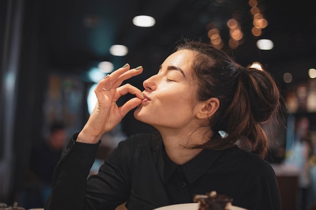 Nahaufnahme einer Frau, die Schokoladenkuchen in einem Café isst, selektiver Fokusrauscheffekt