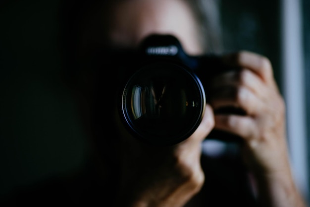 Nahaufnahme einer Frau, die zu Hause durch eine Kamera fotografiert