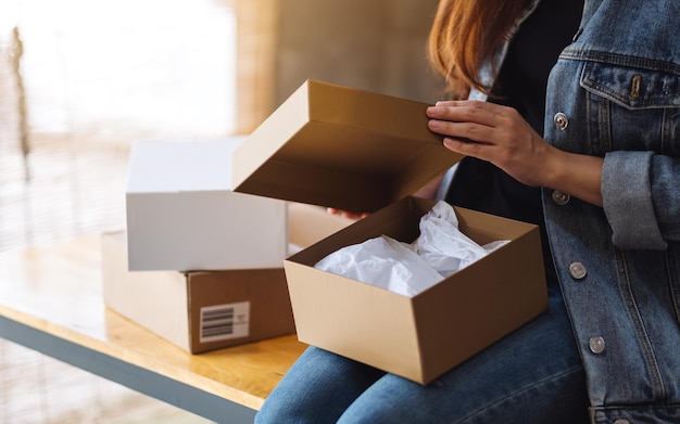 Nahaufnahme einer Frau, die zu Hause einen Postpaketkasten für die Lieferung und das Online-Shopping-Konzept empfängt und öffnet