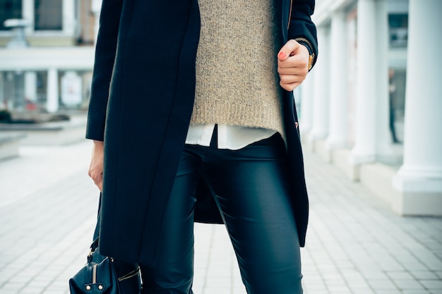 Nahaufnahme einer Frau in einem Pullover, Mantel, schwarzen Hosen