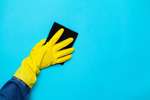 Nahaufnahme einer Frau in gelben Handschuhen mit einem Putzlappen.