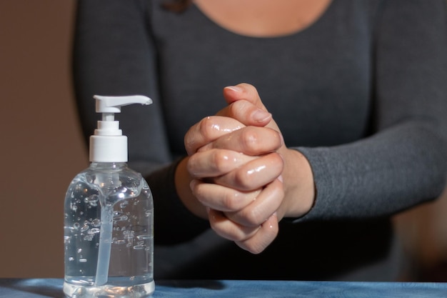 Nahaufnahme einer Frau mit einer Hand, die eine Glasflasche auf dem Tisch hält