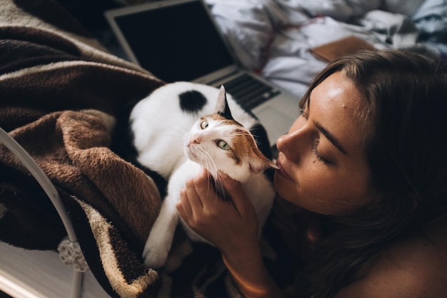 Nahaufnahme einer Frau mit einer Katze im Bett zu Hause