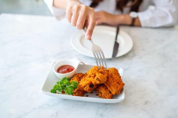 Nahaufnahme einer Frau mit Gabel, um Brathähnchen im Restaurant zu essen?