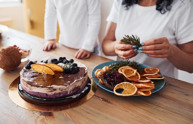 Foto nahaufnahme einer frau mit ihrer enkelin, die diätischen kuchen in der küche zubereitet