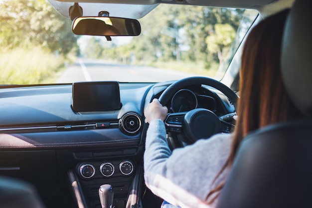 Nahaufnahme einer Frau mit Lenkrad beim Autofahren auf der Straße