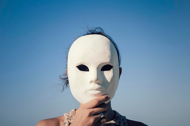 Nahaufnahme einer Frau mit Maske gegen den Himmel