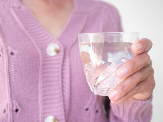 Nahaufnahme einer Frau mit Pullover, die reines Wasser in Glas hält, trink Wasser für Ernährung und Gesundheitskonzept authentische Hautbräune asiatisches Thailand