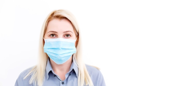 Nahaufnahme einer Frau mit Schutzmaske, die den Kopierraum beiseite sieht, isoliert auf blauem Hintergrund. Grippe, Allergie, Schutz vor Viren, Coronavirus-Pandemie - Covid-19. Werbung für medizinische Masken