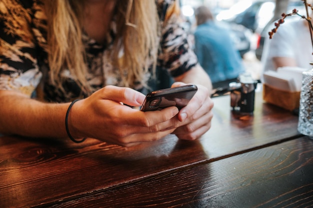 Foto nahaufnahme einer frau mit smartphone auf dem tisch