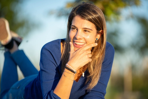 Foto nahaufnahme einer fröhlichen frau, die bei sonnenuntergang in einem park im freien lächelt und wegblickt