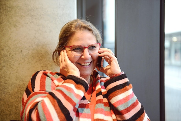 Nahaufnahme einer fröhlichen reifen Frau, die im Freien telefoniert