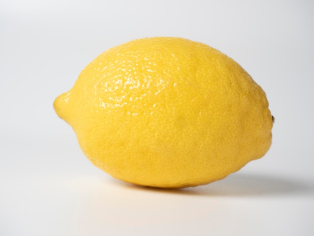 Nahaufnahme einer gelben reifen Zitrone, die auf einem weißen Hintergrund liegt Seitenansicht selektiver Fokus Studioaufnahme