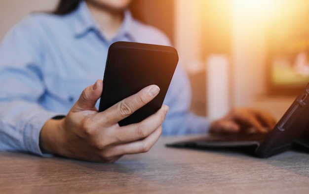 Nahaufnahme einer Geschäftsfrau, die mit Smartphone und Laptop und digitalem Tablet-Computer in einem modernen Büro mit virtuellem Symboldiagramm arbeitet