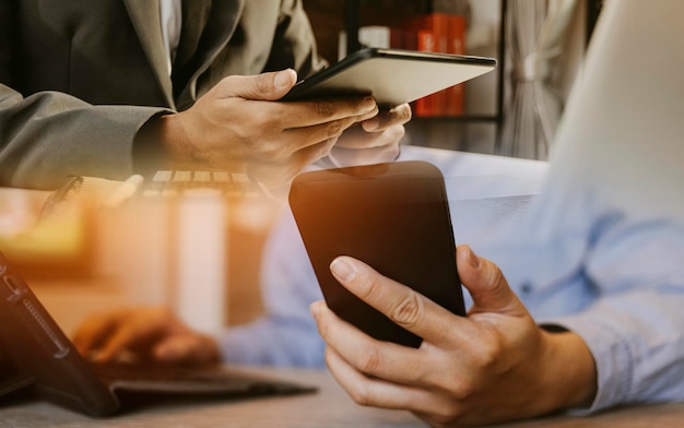 Nahaufnahme einer Geschäftsfrau, die mit Smartphone und Laptop und digitalem Tablet-Computer in einem modernen Büro mit virtuellem Symboldiagramm arbeitet