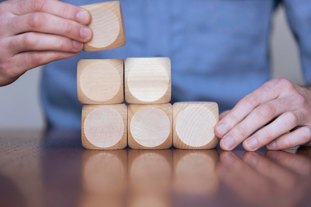 Nahaufnahme einer Geschäftsperson, die große Holzklötze arrangiert Geschäftsstrategie und -lösungen