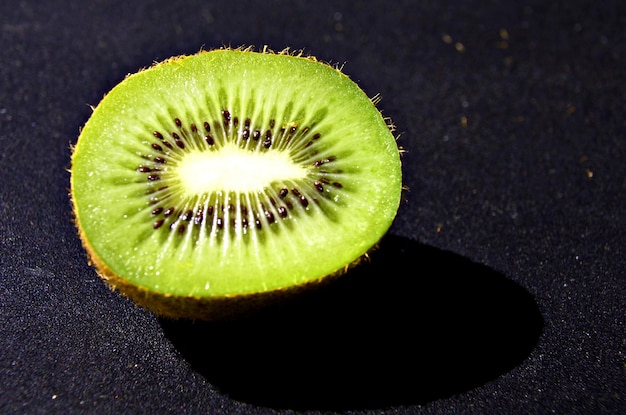 Nahaufnahme einer geschnittenen Kiwi auf schwarzem Hintergrund isoliert.