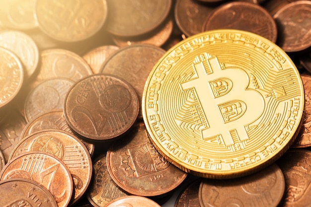 Nahaufnahme einer glänzenden goldenen Bitcoin auf einem Haufen Kupfer-Euro-Münzen