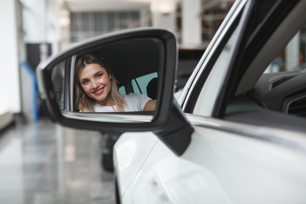 Nahaufnahme einer glücklichen Frau, die im Autoseitenspiegel lächelt, Kopienraum