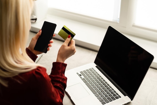 Nahaufnahme einer glücklichen Frau, die online mit einem Laptop kauft und mit einer Kreditkarte bezahlt