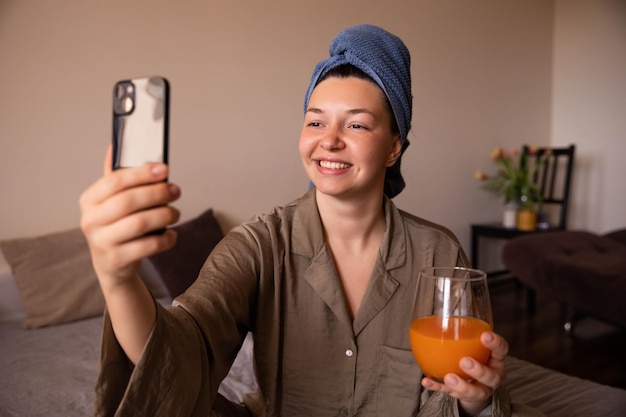 Nahaufnahme einer glücklichen Frau, die zu Hause ein Selfie mit einem Cocktail macht