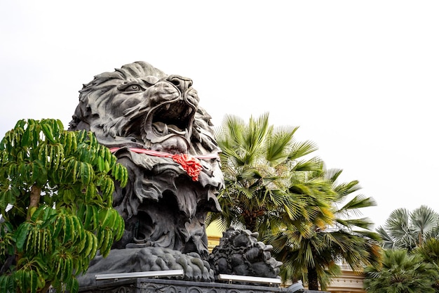 Nahaufnahme einer großen schwarzen Löwenstatue mit rotem Schal, die vor dem Gebäude von Laos sitzt