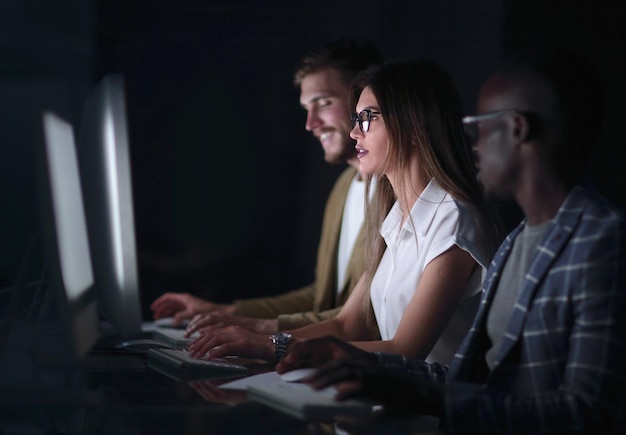 Nahaufnahme einer Gruppe junger Leute, die an Computern arbeitenFoto auf schwarzem Hintergrund