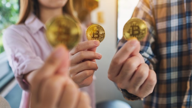 Nahaufnahme einer Gruppe von Menschen, die Bitcoins in goldener Farbe in den Händen halten und zeigen