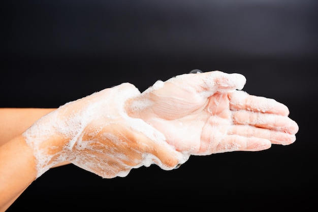 Foto nahaufnahme einer hand, die ein blatt vor schwarzem hintergrund hält