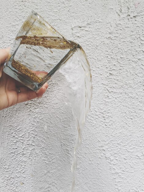 Foto nahaufnahme einer hand, die ein getränk gegen die wand gießt