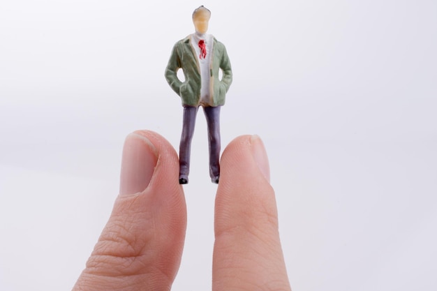 Nahaufnahme einer Hand, die eine Figur vor weißem Hintergrund hält