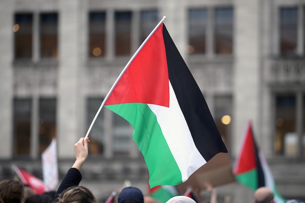 Nahaufnahme einer Hand, die eine Flagge gegen ein Gebäude in der Stadt hält