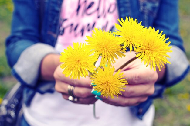 Foto nahaufnahme einer hand, die eine gelbe blume hält