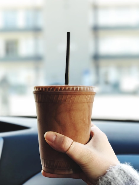 Foto nahaufnahme einer hand, die eine kaffeetasse auf dem tisch hält