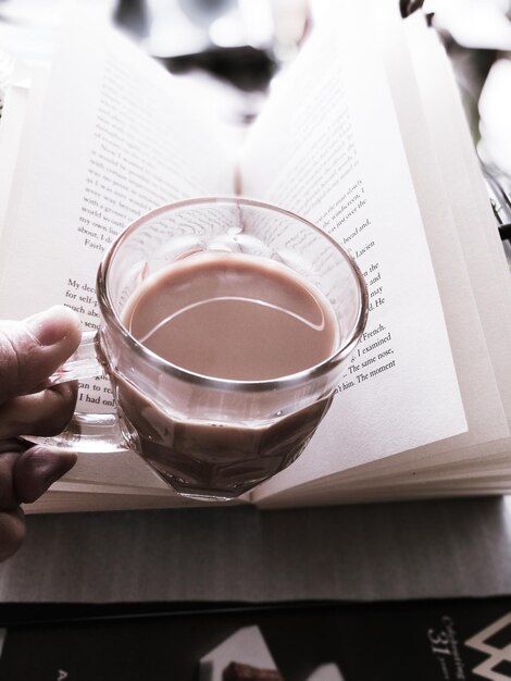 Foto nahaufnahme einer hand, die eine kaffeetasse auf dem tisch hält