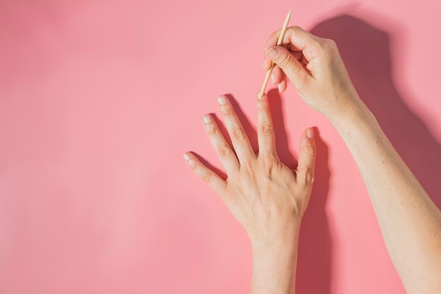 Foto nahaufnahme einer hand, die eine rosa blume über einem farbigen hintergrund hält