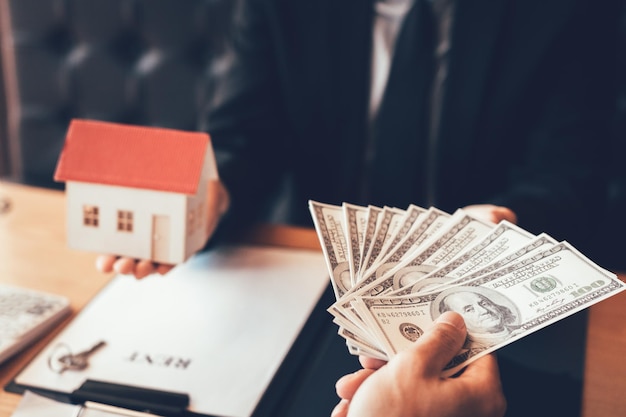 Nahaufnahme einer Hand, die einem Immobilienmakler Papierwährung gibt