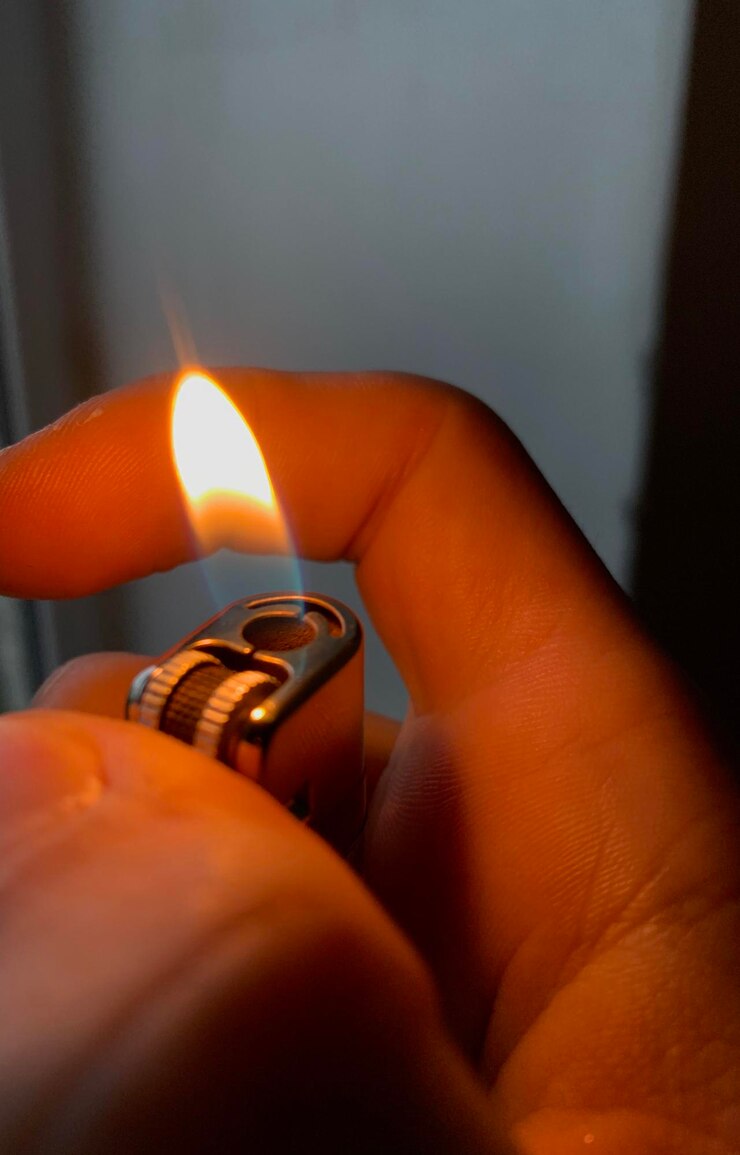 Foto nahaufnahme einer hand, die einen angezündeten zigarettenzünder hält