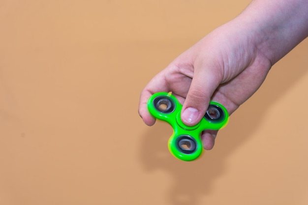 Nahaufnahme einer Hand, die einen Fidget-Spinner gegen einen braunen Hintergrund hält