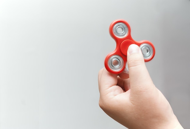 Nahaufnahme einer Hand, die einen Fidget-Spinner vor weißem Hintergrund hält
