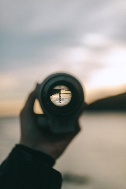 Foto nahaufnahme einer hand, die einen monokular gegen den himmel hält