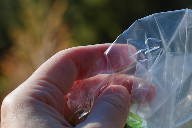 Foto nahaufnahme einer hand, die einen plastikbeutel im freien hält