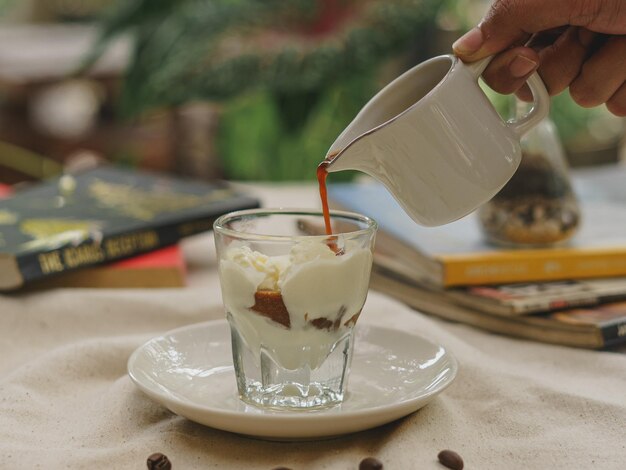 Foto nahaufnahme einer hand, die kaffee in ein glas gießt