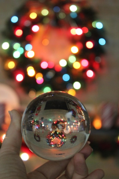 Foto nahaufnahme einer hand, die nachts einen beleuchteten weihnachtsbaum hält