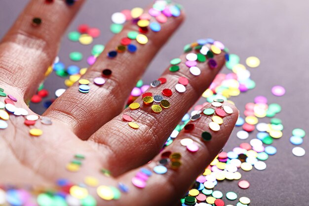 Foto nahaufnahme einer hand mit farbenfrohen pailletten