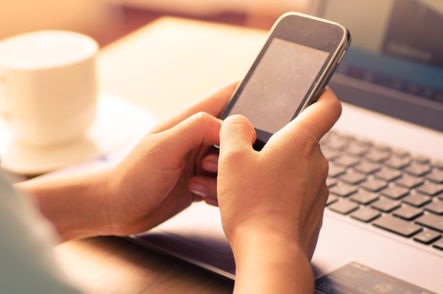 Nahaufnahme einer Hand mit Mobiltelefon auf dem Tisch