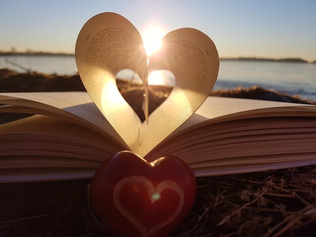 Foto nahaufnahme einer herzform auf einem buch gegen den himmel bei sonnenuntergang