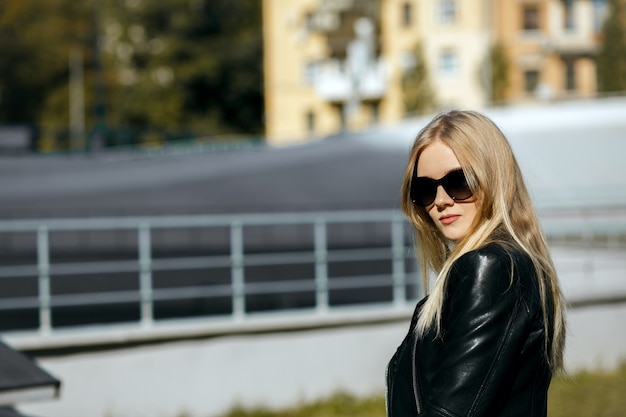 Nahaufnahme einer hübschen blonden Frau mit schwarzer Lederjacke und Sonnenbrille. Platz für Text