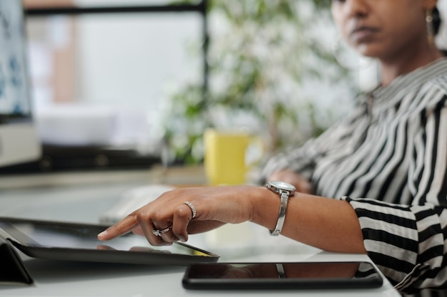 Nahaufnahme einer jungen Designerin, die am Arbeitsplatz auf den Tablet-Bildschirm zeigt