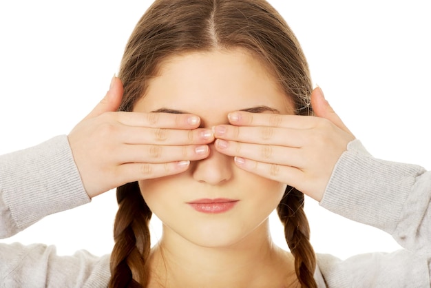 Foto nahaufnahme einer jungen frau, die die augen vor weißem hintergrund bedeckt